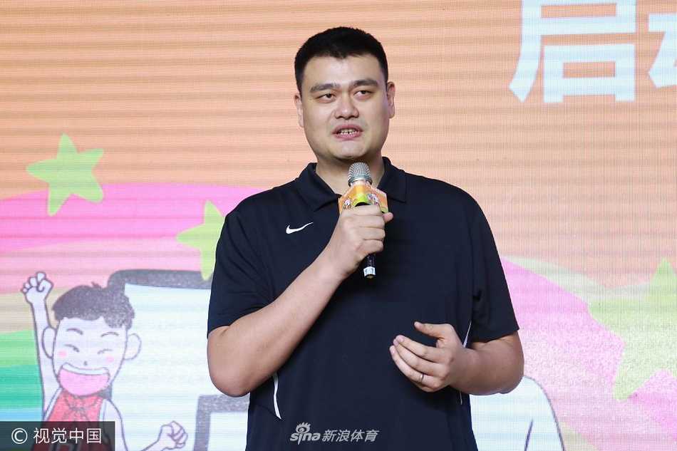 姚明身着深色西装现身篮球季启动仪式现场，他一出现便成为全场焦点，高大的身影在人群中格外醒目，脸上带着温和的笑意，正向四周挥手致意，仿佛一位邻家大哥般亲切。