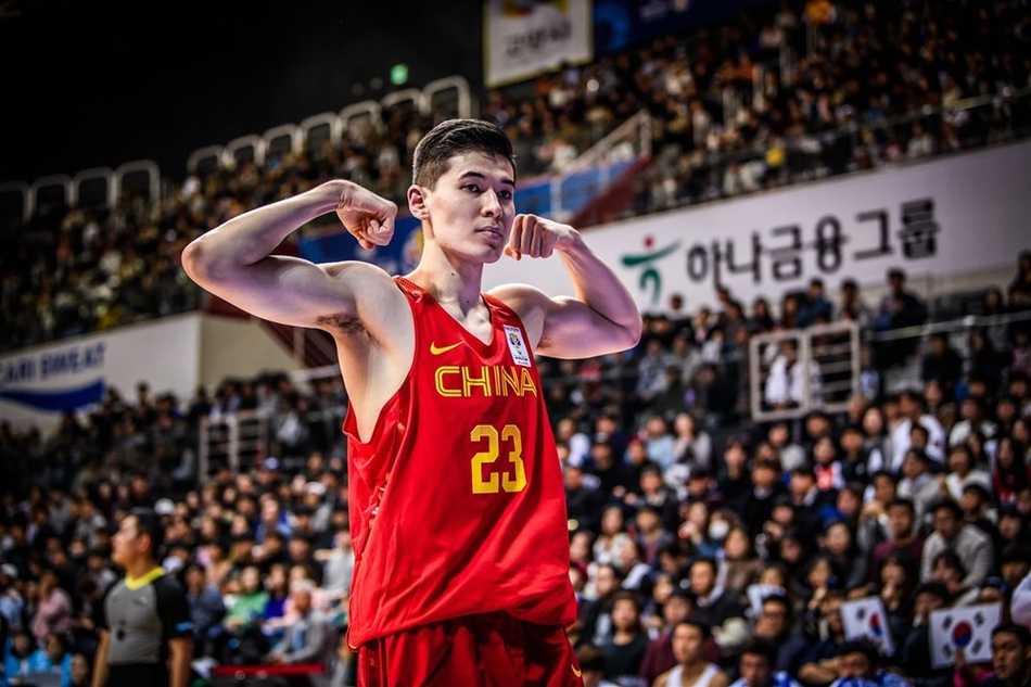 王哲林在篮下卡位抢下进攻篮板，面对三名韩国队员的合围，他奋力将球举过头顶，肌肉线条充满力量感。