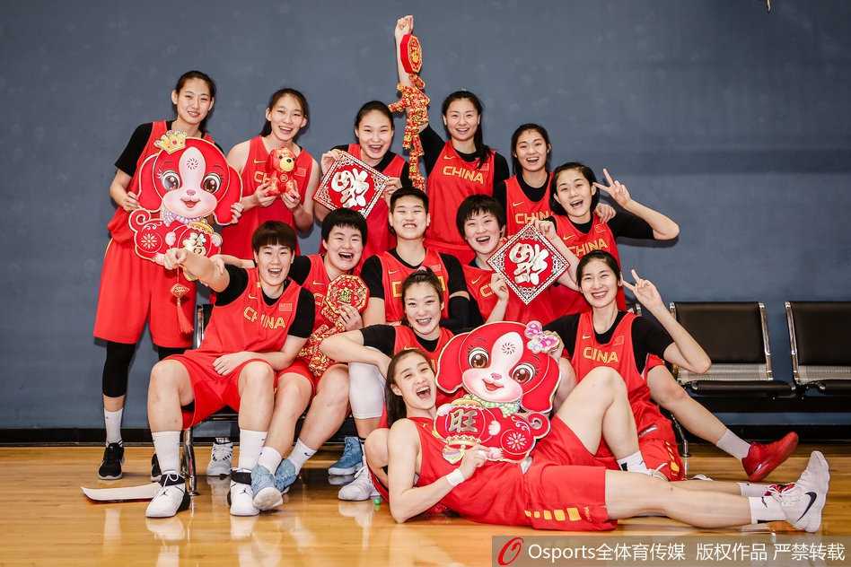 身穿火红国家队队服的女篮姑娘们站成一排，对着镜头比出可爱的“666”手势，身后的新春装饰映衬着她们灿烂如花的笑容，洋溢着青春的朝气与节日的喜庆。