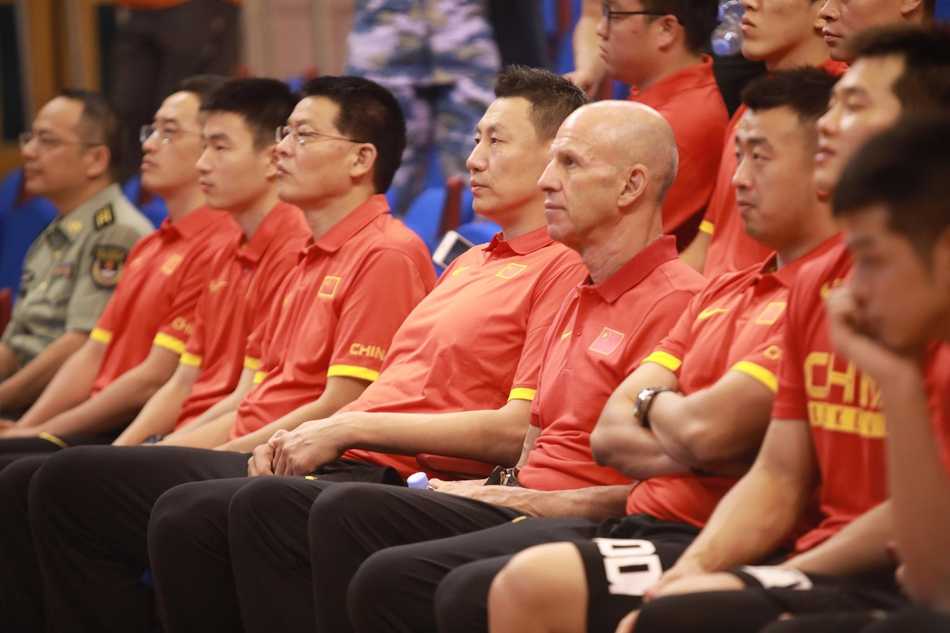 中国男篮红队全体球员与驻香港部队官兵在威武的军舰前整齐列队，一同留下了一张洋溢着笑容与情谊的珍贵大合影，蓝天白云下的迷彩与红色队服交相辉映。