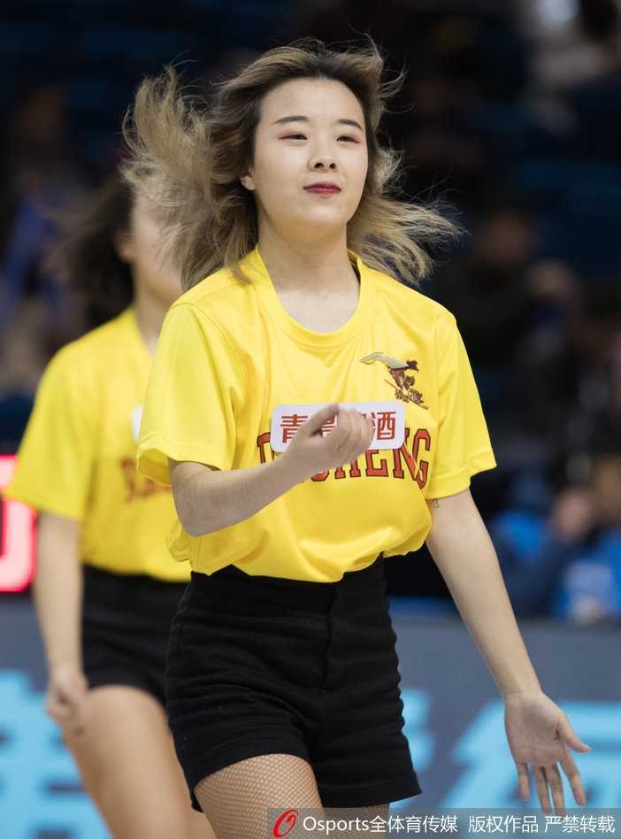 一名篮球宝贝在场地中央展示着优美的舞姿，她双手舒展，身姿曼妙，身后的巨大记分牌显示着同曦队大比分领先的喜人局势，这一刻，胜利与美丽交相辉映。